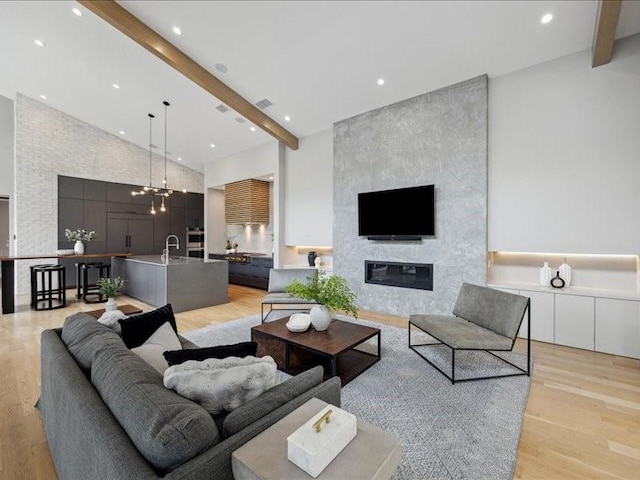 living area with recessed lighting, beamed ceiling, and light wood-type flooring