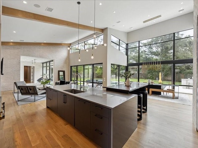 kitchen with dark brown cabinets, a sink, open floor plan, a towering ceiling, and modern cabinets