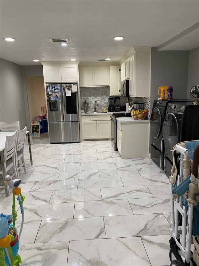 1319 Cherry Spring Dr, Houston, TX 77038 - kitchen with marble finish floor, stainless steel appliances, washing machine and dryer, and visible vents