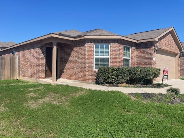view of side of home featuring an attached garage, brick siding, and a yard