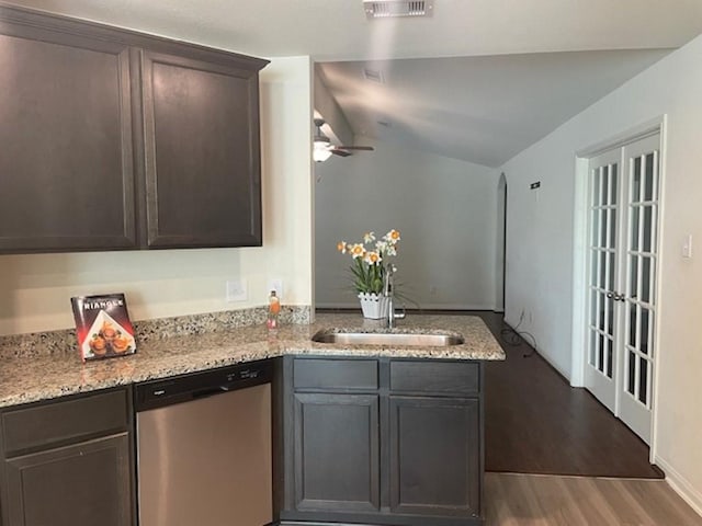 kitchen featuring a sink, light stone countertops, wood finished floors, a peninsula, and stainless steel dishwasher