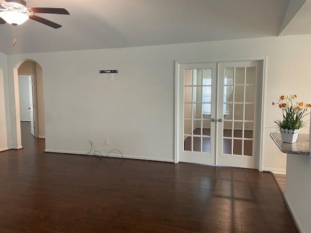 unfurnished room with arched walkways, ceiling fan, french doors, and dark wood-type flooring