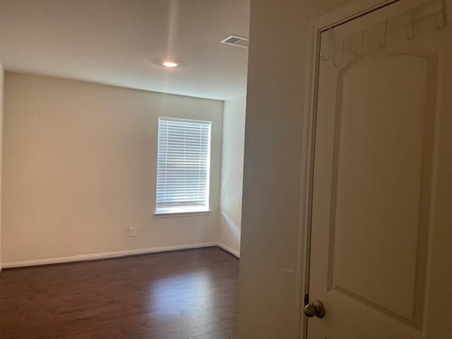 unfurnished room with baseboards, visible vents, and dark wood-style floors