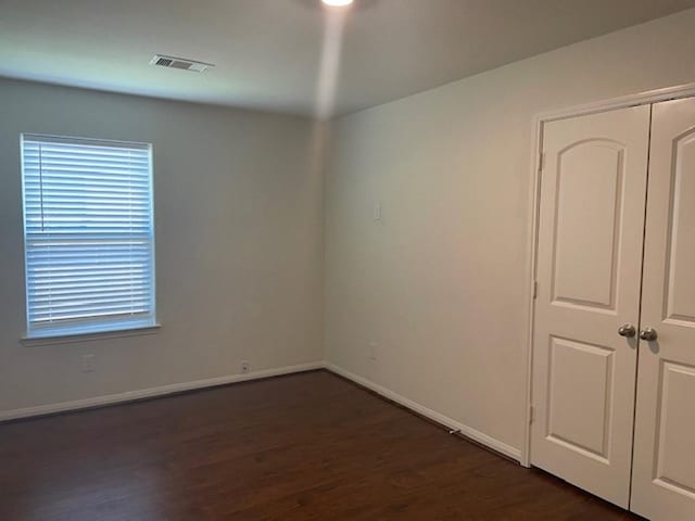 spare room with baseboards, visible vents, and dark wood-type flooring