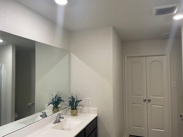 bathroom with toilet, vanity, and visible vents