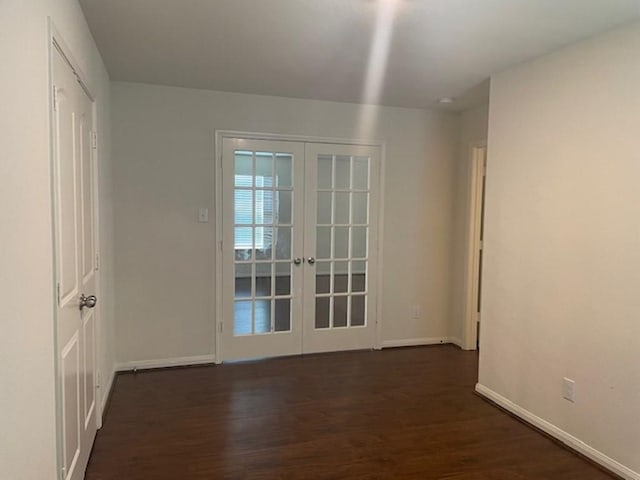 empty room featuring baseboards, dark wood-style flooring, and french doors