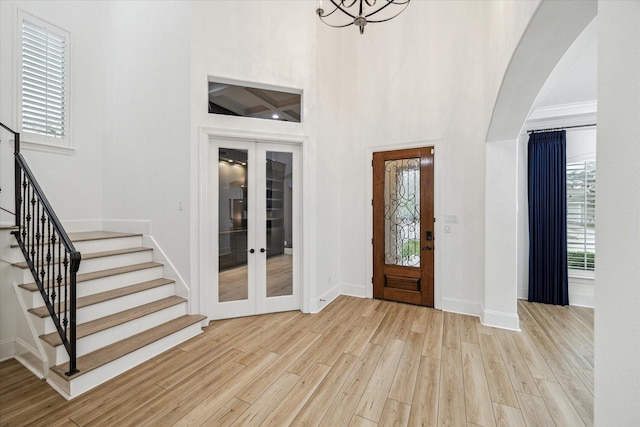 foyer featuring a wealth of natural light, stairway, light wood-style flooring, and french doors