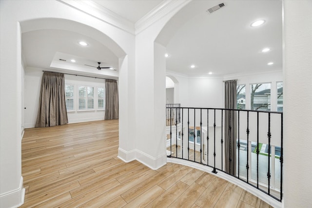 corridor with plenty of natural light, visible vents, ornamental molding, and wood finished floors