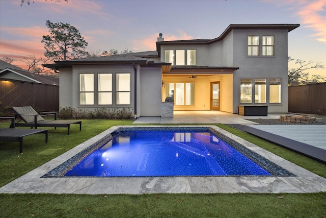 back of property featuring ceiling fan, fence, a fire pit, and stucco siding