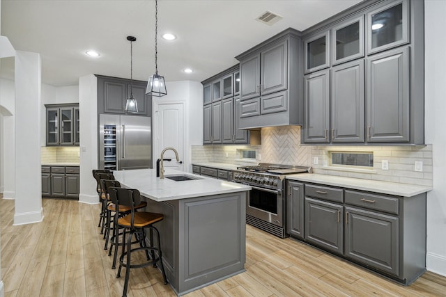kitchen featuring visible vents, a sink, high quality appliances, gray cabinetry, and backsplash