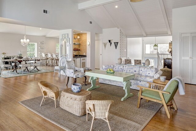 living room with a chandelier, beamed ceiling, high vaulted ceiling, and wood finished floors