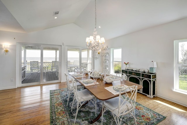 dining space featuring vaulted ceiling, a chandelier, light wood-style flooring, and baseboards