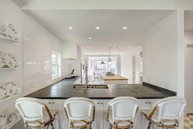 kitchen with a sink, white cabinets, recessed lighting, decorative light fixtures, and a peninsula