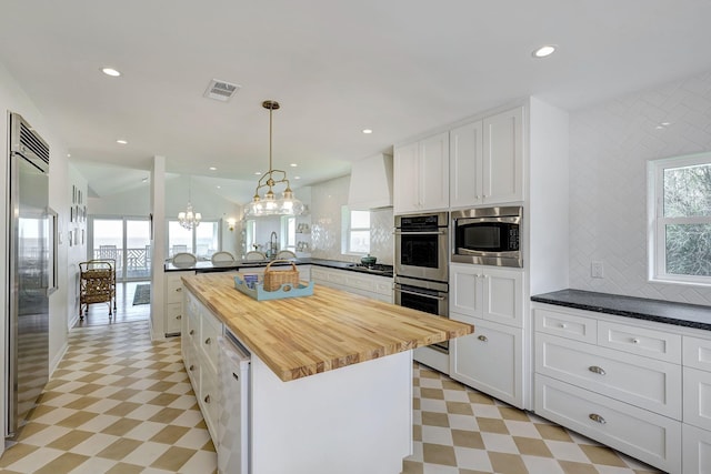 kitchen featuring light floors, wood counters, built in appliances, a peninsula, and recessed lighting