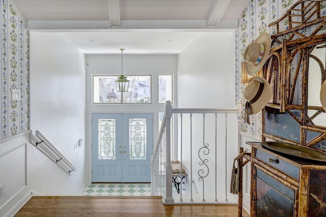 foyer entrance with beamed ceiling, wood finished floors, and french doors