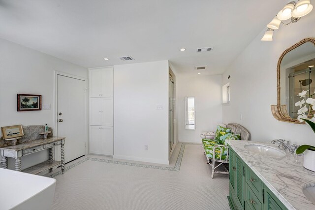 kitchen featuring green cabinets, a sink, recessed lighting, light stone countertops, and baseboards