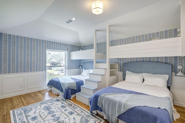 bedroom featuring wallpapered walls, wood finished floors, and lofted ceiling