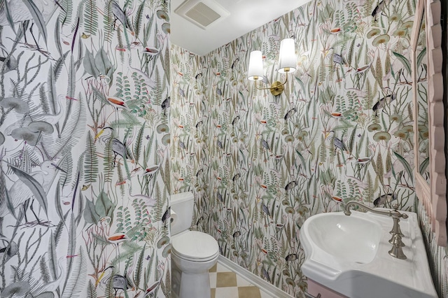 bathroom featuring wallpapered walls, toilet, and a sink