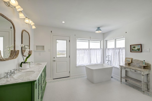 full bath featuring a soaking tub, baseboards, double vanity, and recessed lighting