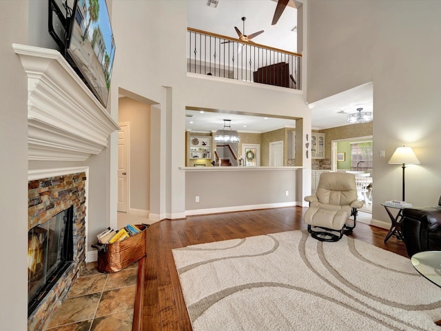 15415 Parkwood Way, Houston, TX 77059 - living room with ceiling fan with notable chandelier, a towering ceiling, a stone fireplace, wood finished floors, and baseboards