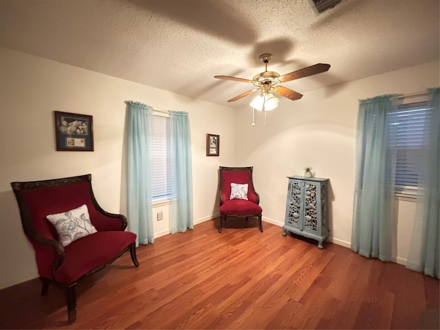sitting room featuring a textured ceiling, visible vents, baseboards, wood finished floors, and ceiling fan