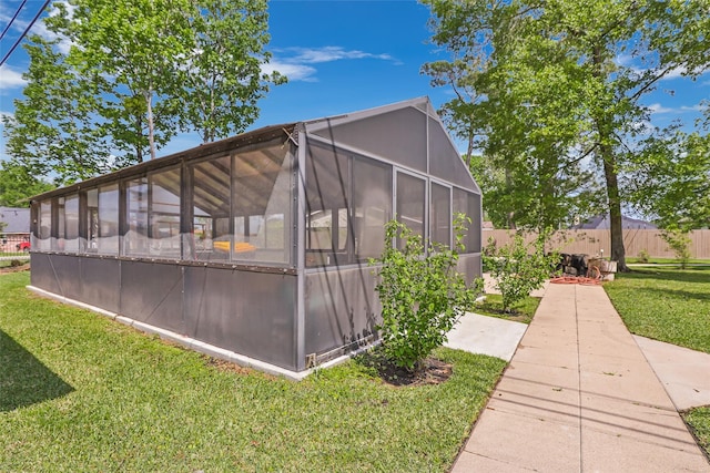 18510 Bluffview Dr, Crosby, TX 77532 - view of side of home featuring a lawn, an outdoor structure, fence, and a greenhouse