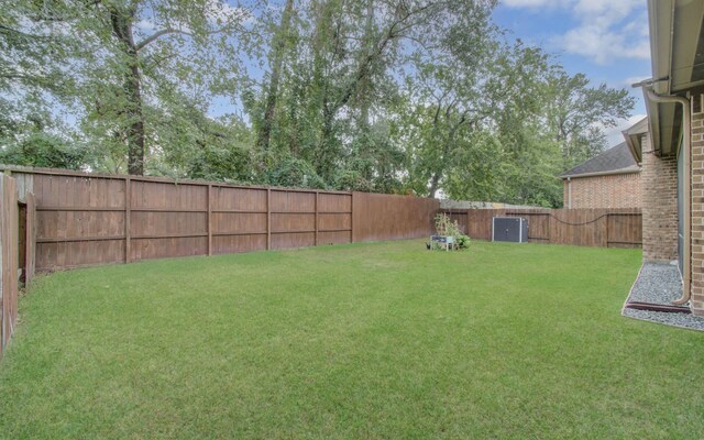 view of yard with central AC unit and a fenced backyard