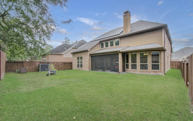 back of house featuring a yard, a fenced backyard, brick siding, and a chimney