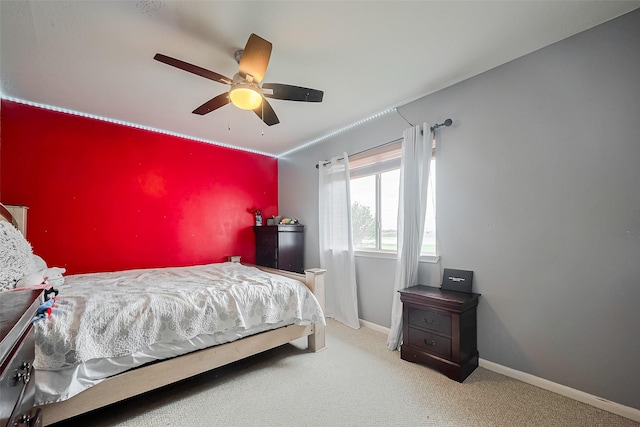 bedroom with baseboards, ceiling fan, carpet, and an accent wall
