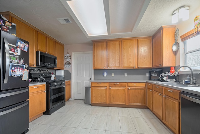 kitchen with a sink, freestanding refrigerator, double oven range, stainless steel dishwasher, and visible vents