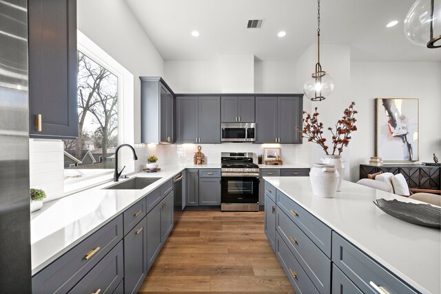 kitchen featuring dark wood-style flooring, recessed lighting, tasteful backsplash, appliances with stainless steel finishes, and a sink