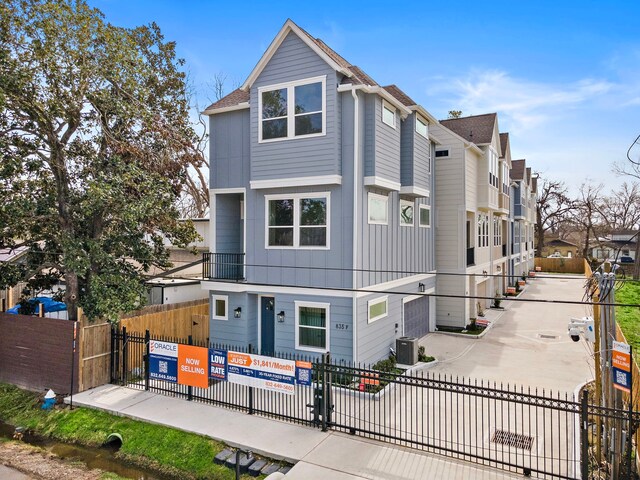 view of front facade with a residential view, central AC, and fence