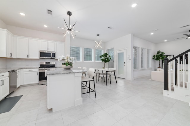 15115 Parkland Canyon Dr, Cypress, TX 77433 - kitchen featuring appliances with stainless steel finishes, a chandelier, white cabinets, light stone countertops, and recessed lighting
