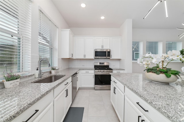15115 Parkland Canyon Dr, Cypress, TX 77433 - kitchen featuring stainless steel appliances, a sink, decorative backsplash, white cabinetry, and light tile patterned floors