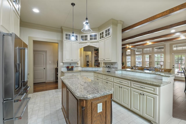 kitchen featuring a peninsula, arched walkways, stainless steel fridge, glass insert cabinets, and a kitchen island