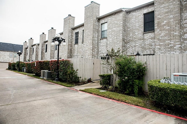 view of property with central air condition unit and fence
