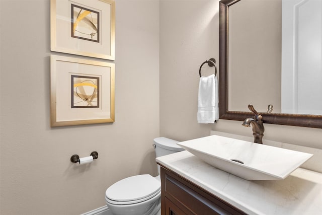 half bathroom featuring toilet, vanity, and baseboards