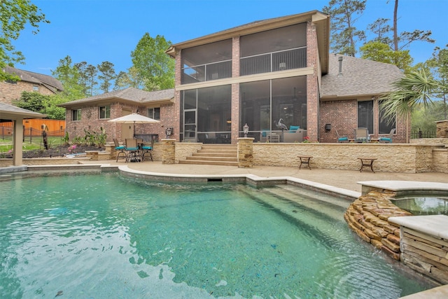view of pool with a sunroom, a patio, fence, and a pool with connected hot tub