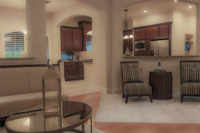 living area featuring arched walkways, recessed lighting, and baseboards