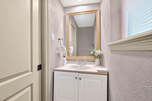 bathroom with a textured wall and vanity