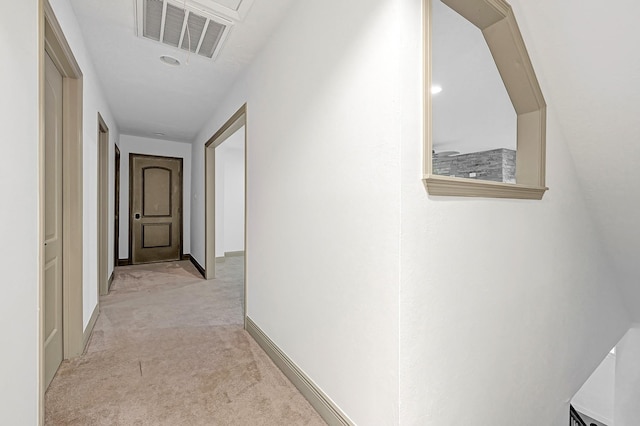 hall featuring visible vents, baseboards, and light carpet
