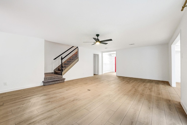 unfurnished living room with stairway, baseboards, a ceiling fan, and wood finished floors