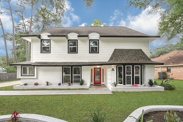 view of front of house featuring a front yard, roof with shingles, brick siding, central AC unit, and a porch