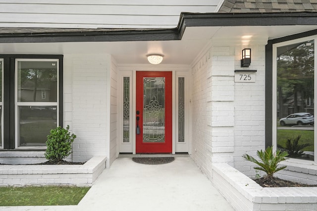 view of exterior entry with covered porch and brick siding