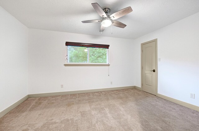unfurnished room with ceiling fan, light colored carpet, and baseboards