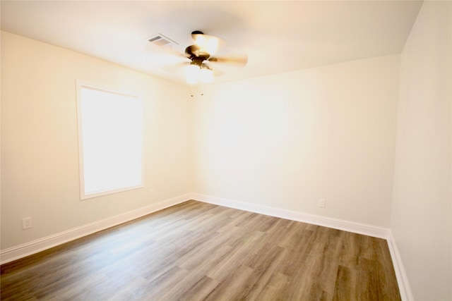 empty room with wood finished floors, baseboards, and a ceiling fan
