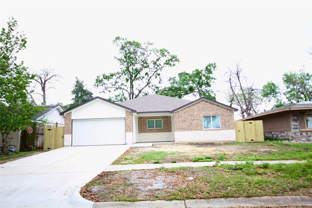 single story home with a garage, brick siding, driveway, and fence