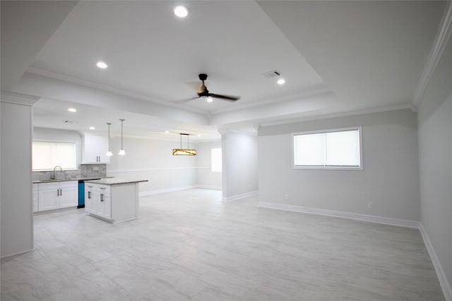 unfurnished living room featuring crown molding, a sink, a ceiling fan, a raised ceiling, and plenty of natural light