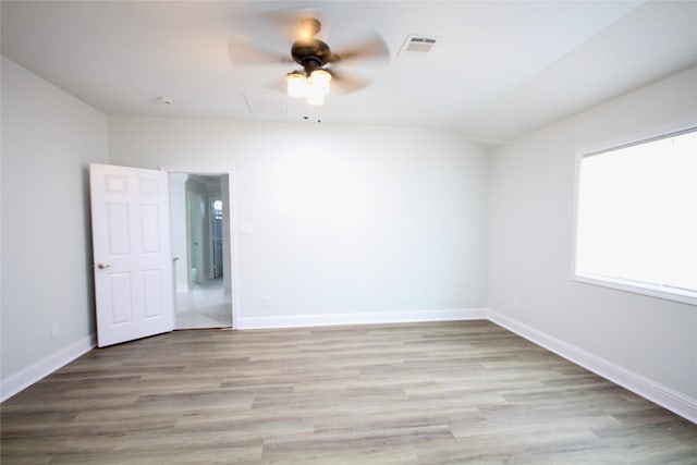 empty room with ceiling fan, wood finished floors, baseboards, and vaulted ceiling