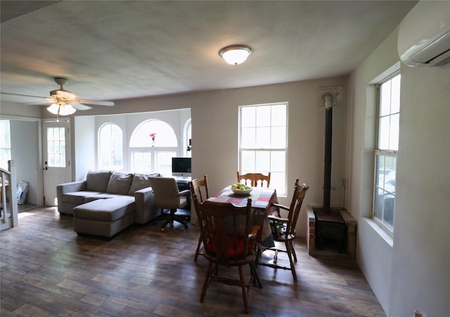 dining area featuring dark wood-style floors, an AC wall unit, a wood stove, and ceiling fan